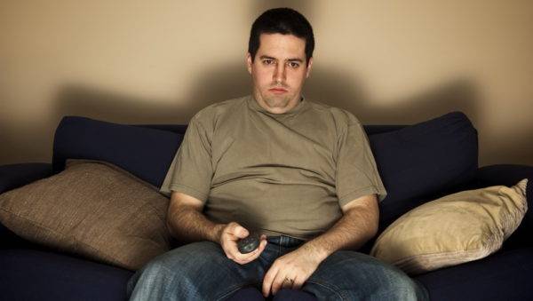 bored-overweight-man-sits-on-the-sofa